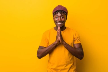 Sarı arka planda rastalar takan genç siyahi bir adam, bir plan kuruyor, bir fikir kuruyor..