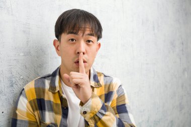 Genç Çinli adamın yüzü kapalı bir şekilde ya sır saklıyor ya da sessizlik istiyor.