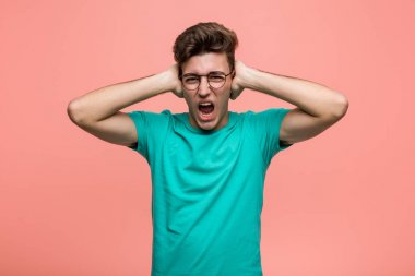 Genç, havalı, beyaz bir adam, kulaklarını elleriyle kapatıyor ve yüksek sesli sesler duymamaya çalışıyor..