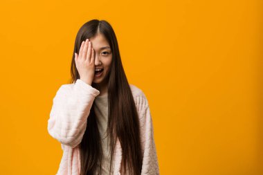 Pijamalı genç Çinli kadın yüzünün yarısını avuç içiyle örterek eğleniyor..