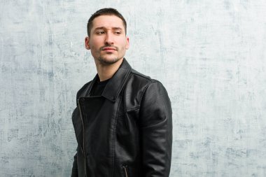 Genç rockçı gülümseyerek, neşeli ve keyifli bir şekilde yana bakıyor..