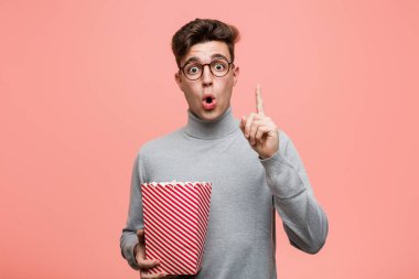 Elinde patlamış mısır kovası olan genç entelektüel bir adam rahatlamış fotokopi odasına bakan bir şey düşünüyor..