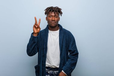 Genç Afrikalı siyah adam pijama giyiyor. İki numarayı parmaklarıyla gösteriyor..