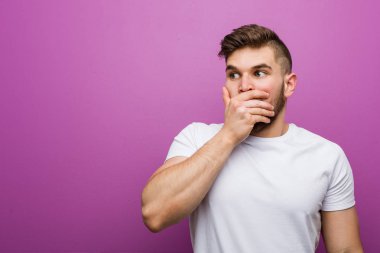 Genç yakışıklı beyaz adam düşünceli bir şekilde bir fotokopi odasına bakıyor ağzını eliyle kapatıyor..