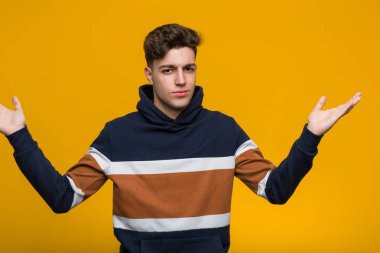 Kapüşonlu genç, havalı bir adam şüpheleniyor ve jestini sorgularken omuzlarını silkiyor..