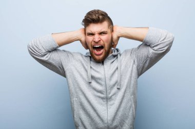 Genç yakışıklı jimnastikçi, kulaklarını elleriyle kapatıyor..