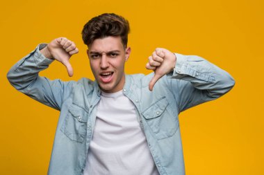 Kot gömlek giyen genç ve yakışıklı bir öğrenci başparmağını aşağı gösteriyor ve hoşlanmadığını ifade ediyor..