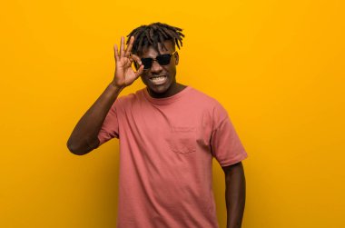 Güneş gözlüğü takan genç siyahi bir adam heyecanlı..