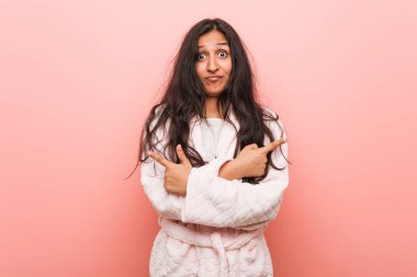 Pijama puanı giyen genç Hintli kadın iki seçenek arasında seçim yapmaya çalışıyor..