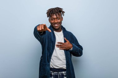 Genç Afrikalı siyah adam pijama puanı takıyor başparmak uzakta, gülüyor ve kaygısız..