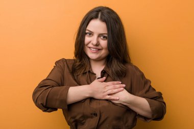 Genç kıvrımlı Rus kadın dost canlısı bir ifadeye sahip, avuçlarını göğsüne bastırıyor. Aşk konsepti.