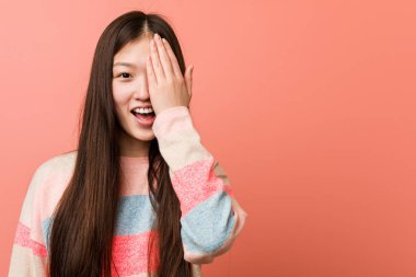 Genç havalı Çinli kadın yüzünün yarısını avuç içiyle örterek eğleniyor..