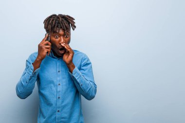 Genç Rasta siyahi adam elinde bir telefonla heyecanla bağırıyor..