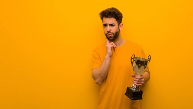 Elinde kupa tutan genç adam kuşkulu ve kafası karışık