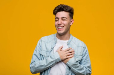 Kot gömlek giyen genç ve yakışıklı bir öğrenci gülüyor. Elini yüreğine koyuyor, mutluluk kavramını koruyor..