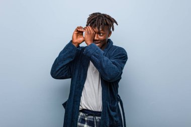 Genç Afrikalı siyah adam pijama giymiş uzaklara bakıyor ve onu alnında tutuyor..