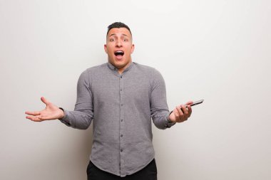 Zaferi ya da başarıyı kutlayan bir telefon tutan genç Latin adam.