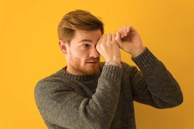 Genç kızıl saçlı adam, dürbün hareketi yapıyor.