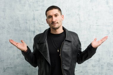 Genç rockçı adamın kafası karışık ve şüpheci. Kopya alanını tutmak için ellerini kaldırıyor..