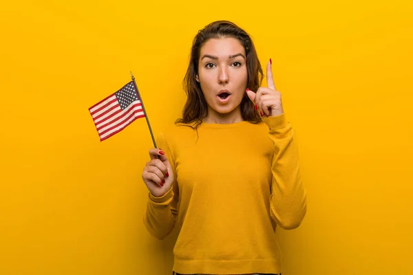 Young woman holding an united states flag having some great idea, concept of creativity.