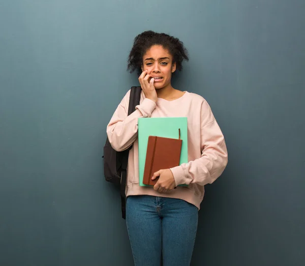 Young student black woman desperate and sad. She is holding books.