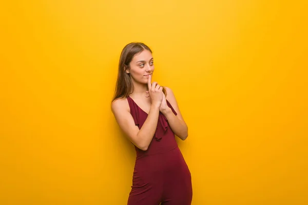 Young natural woman wearing a red dress against an orange wall — Stock Photo, Image