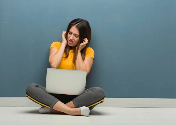 Молодая Женщина Сидящая Полу Ноутбуком Закрывающим Уши Руками — стоковое фото