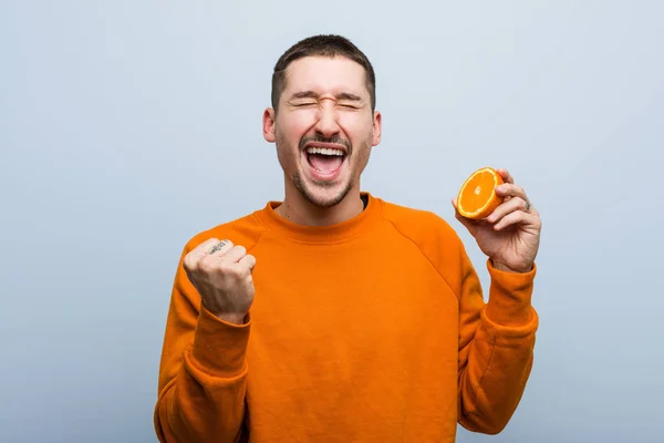 Jeune Homme Caucasien Tenant Une Orange Acclamant Insouciant Excité Concept — Photo