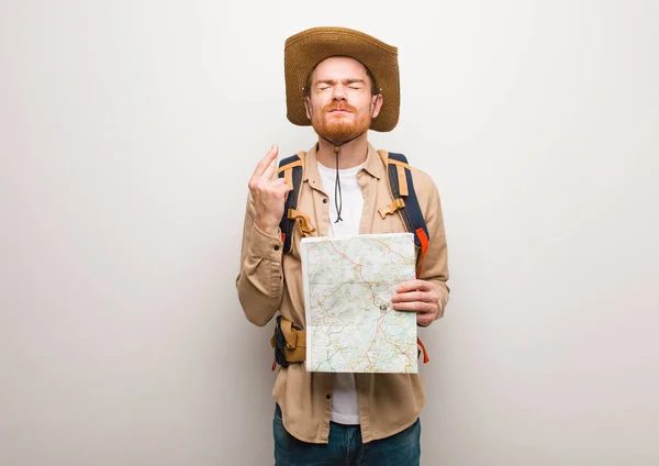 Junger rothaariger Entdecker, der dem Glück die Daumen drückt. eine Karte in der Hand halten. — Stockbild Junger Rothaariger Entdecker Der Dem Glück Die Daumen Drückt Eine — Stockfoto