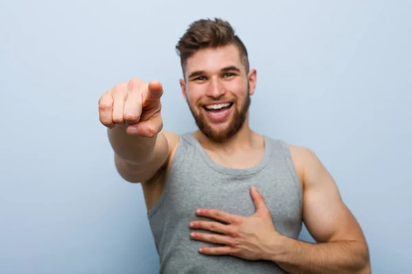 Young Handsome Fitness Man Points Thumb Finger Away Laughing Carefree — ストック写真