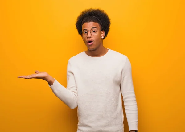 Giovane Uomo Afroamericano Sopra Muro Arancione Che Tiene Qualcosa Sulla — Foto Stock
