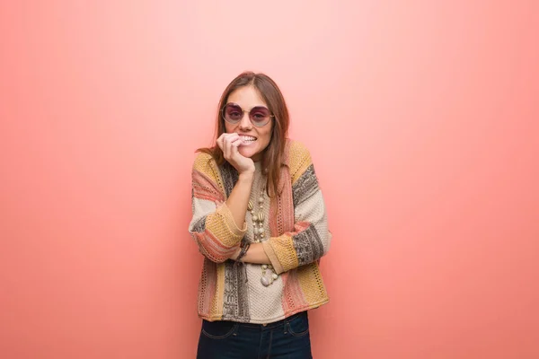 Young hippie woman on pink background biting nails, nervous and very anxious