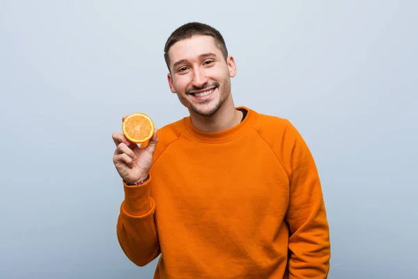 Joven Hombre Caucásico Sosteniendo Una Naranja Feliz Sonriente Alegre — Foto de Stock