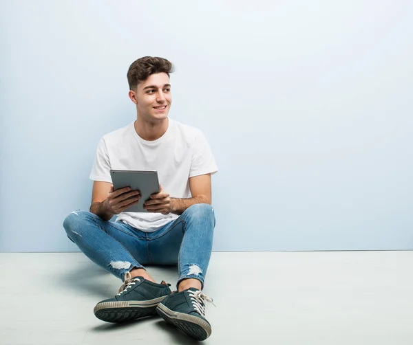 Joven Sosteniendo Una Tableta Sentada Interior Sonriendo Confiado Con Brazos — Foto de Stock