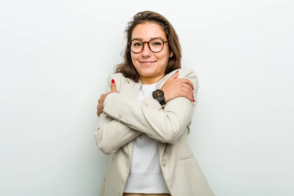 Young european business woman hugs herself, smiling carefree and happy.