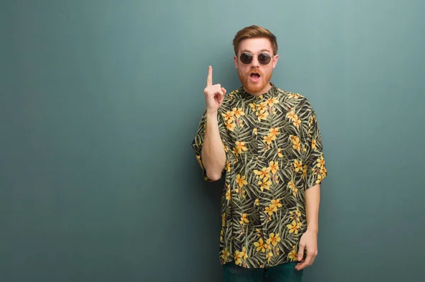 Young redhead man wearing exotic summer clothes having a great idea, concept of creativity