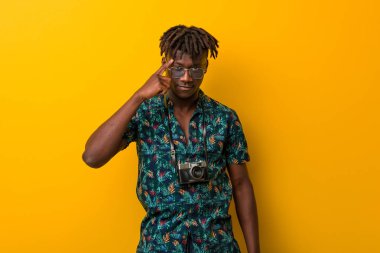 Tatil giysisi giyen genç siyah Rasta tapınağı işaret ediyor, düşünüyor ve bir göreve odaklanıyor..