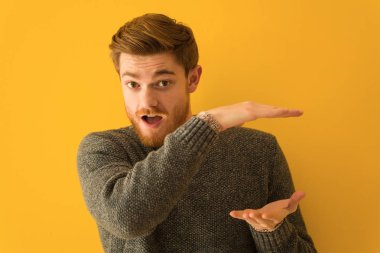 Genç kızıl saçlı adam elinde çok şaşırmış ve şok olmuş bir şey tutuyor.