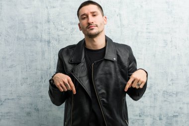 Genç rockçı parmaklarıyla aşağıya doğru işaret ediyor, pozitif duygu..