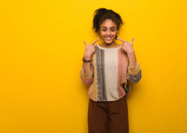 Mavi gözlü genç siyah afro-amerikan kız gülümsüyor, ağız işaret