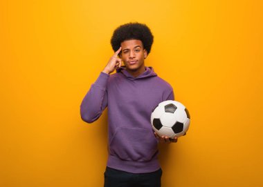 Genç Afro-Amerikan sporcusu elinde futbol topu tutarken bir fikir düşünüyor.