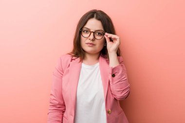 Genç ve cüsseli beyaz bir kadın şakağı parmağıyla göstererek bir göreve odaklanıyor..