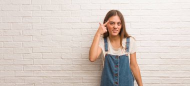 Genç hippi kadın parmağıyla hayal kırıklığı jesti yapıyor.