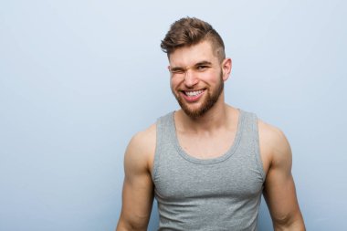 Genç yakışıklı fitness adamı göz kırpıyor, komik, arkadaş canlısı ve kaygısız.