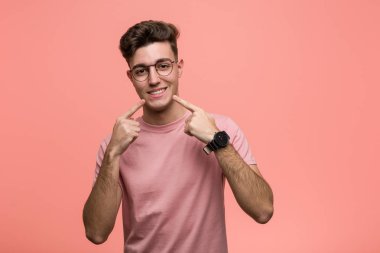 Kafkasyalı genç adam gülümsüyor, parmaklarını ağzına doğrultuyor..