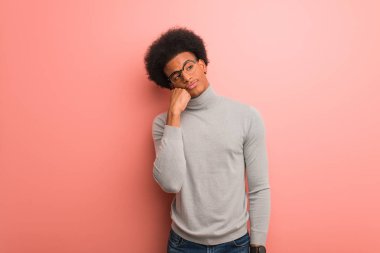 Pembe bir duvarın üzerinde genç afro-amerikan adam bir şey düşünüyor, yan bakıyor