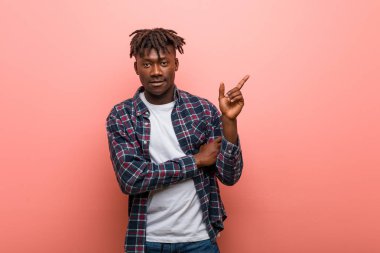 Genç Afrikalı siyah adam işaret parmağıyla işaret ederek gülümsüyor..