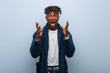 Genç Afrikalı siyah adam pijamalarıyla zaferi ya da başarıyı kutluyor.