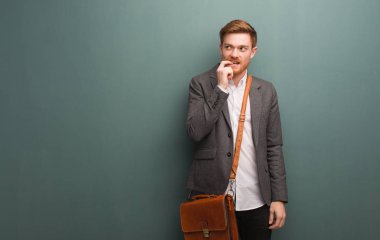 Genç kızıl saçlı iş adamı rahatlamış fotokopi odasına bakan bir şey düşünüyor.