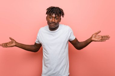 Genç Afrikalı siyahi bir adam şüphe ediyor ve sorgulamada omuzlarını silkiyor..